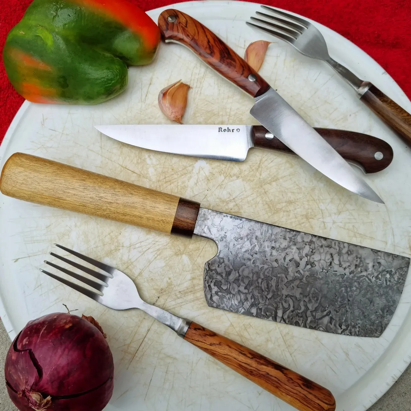 Set de cuchilla de damasco, cuchillos y tenedores de madera sobre una tabla con verduras